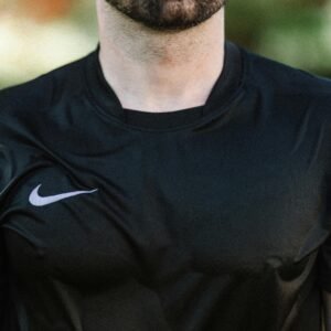 A man wearing a black athletic t-shirt outdoors, showcasing a sporty look and lifestyle.