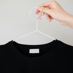 Black t-shirt on hanger with hand holding, perfect for apparel mockups.